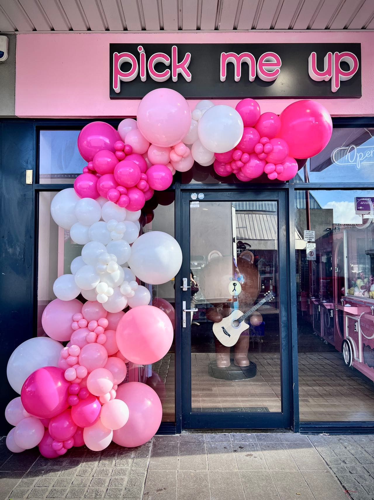 Pink and white balloon arch for store opening with neon signage