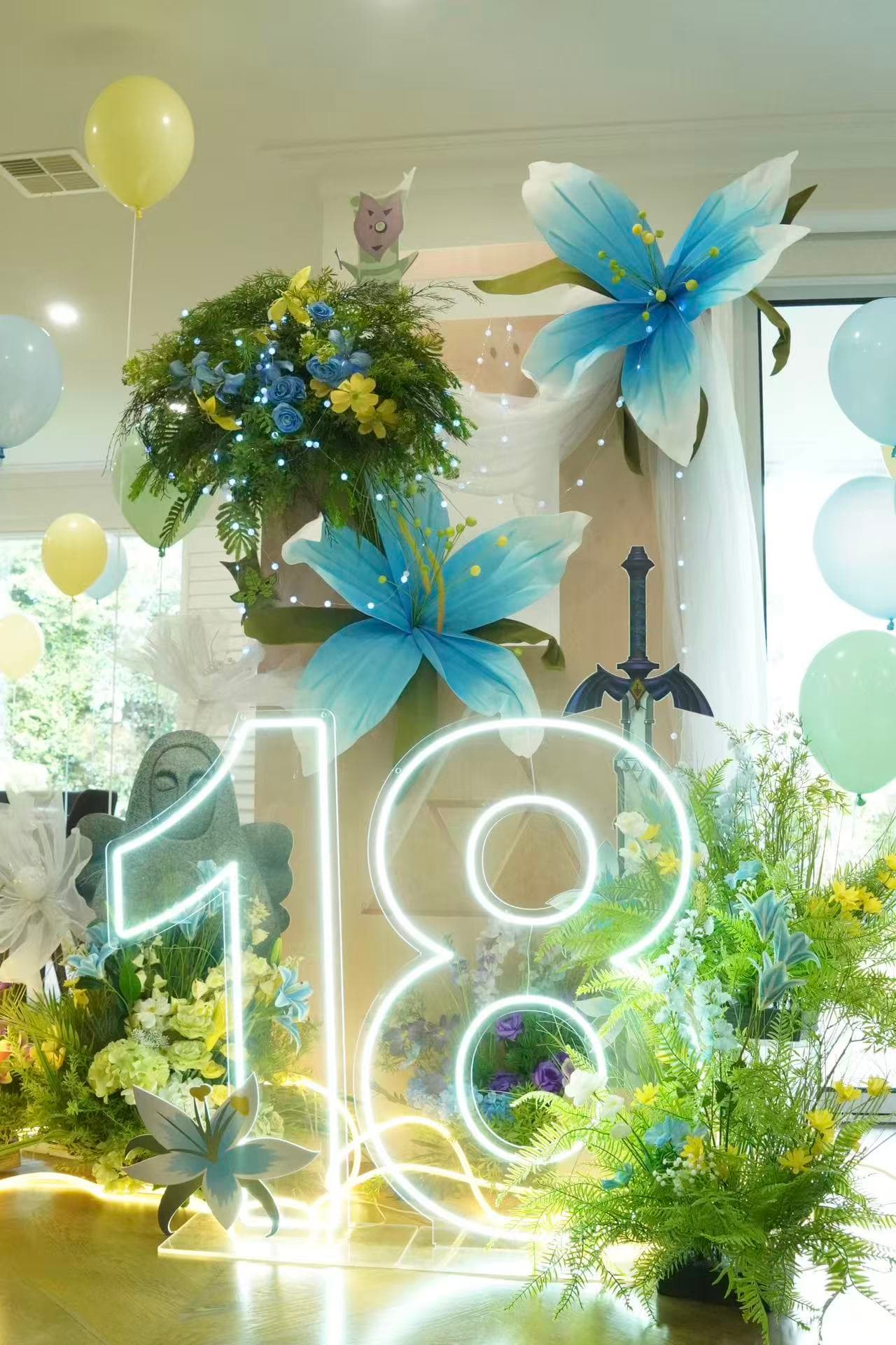 Elegant 18th indoor birthday with blue lily decor, greenery and neon number 18.