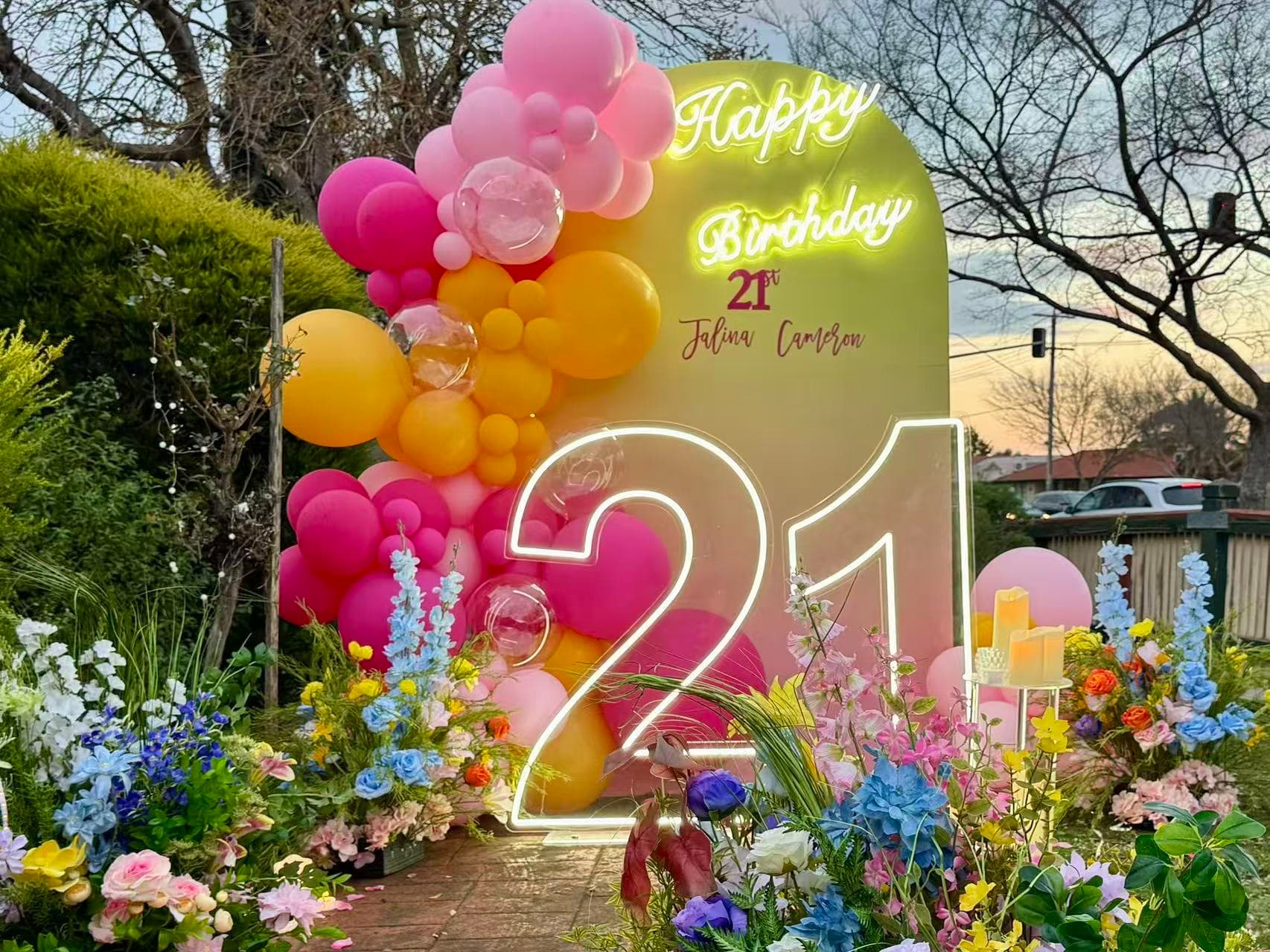 Pink and orange 21st outdoor birthday with neon 21 and lush garden florals.