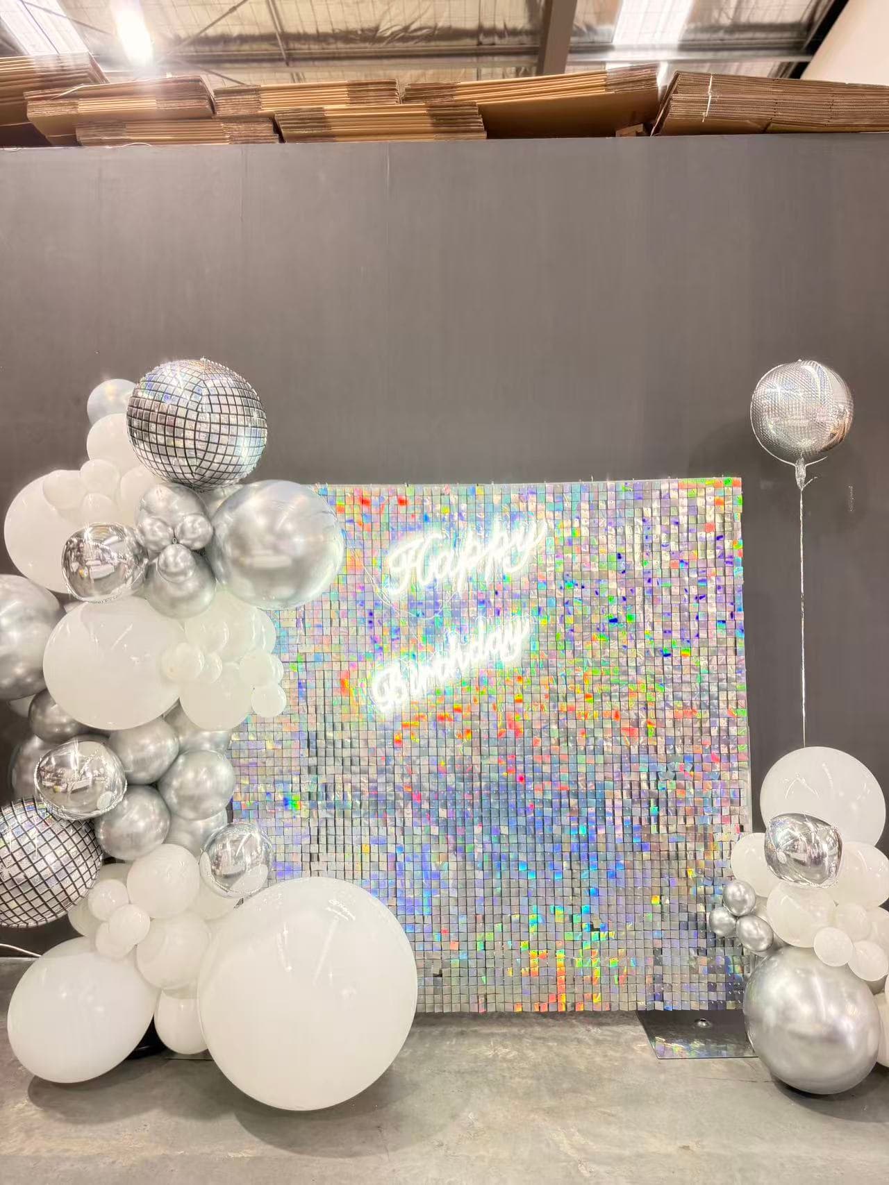 Silver and white sequin wall birthday backdrop with disco accents and balloons.
