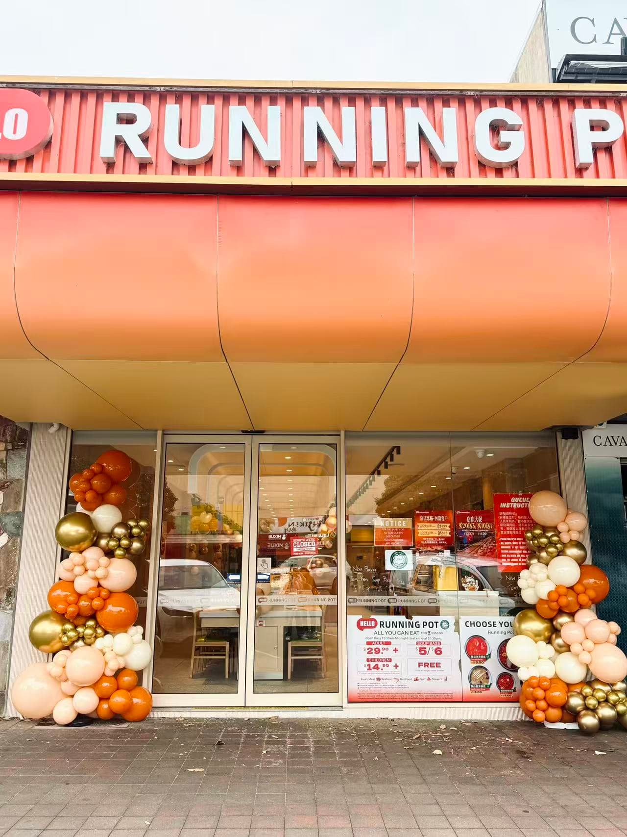 Storefront entrance with orange, gold and white balloon arches and pumpkin-shaped decorations