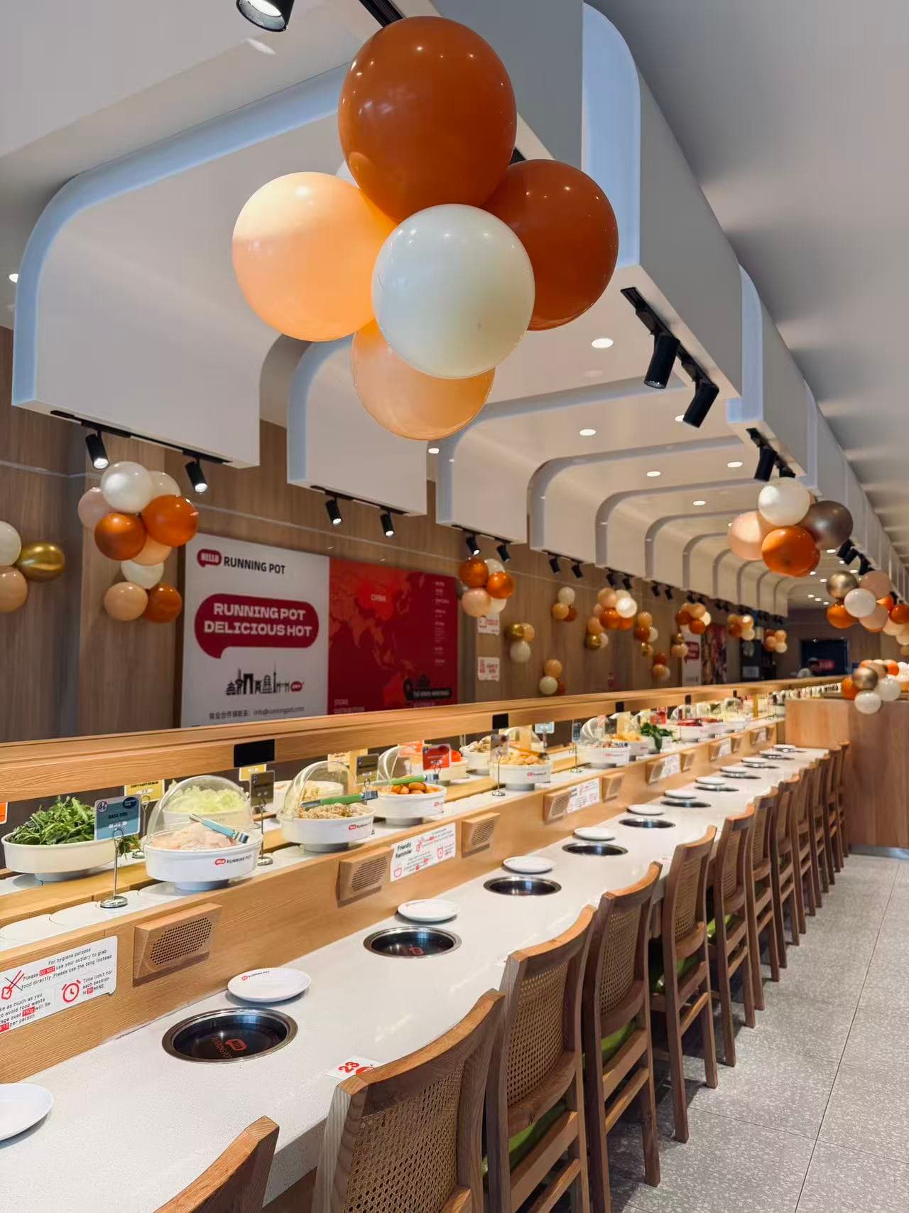 Restaurant interior with warm orange, peach and white ceiling balloon clusters