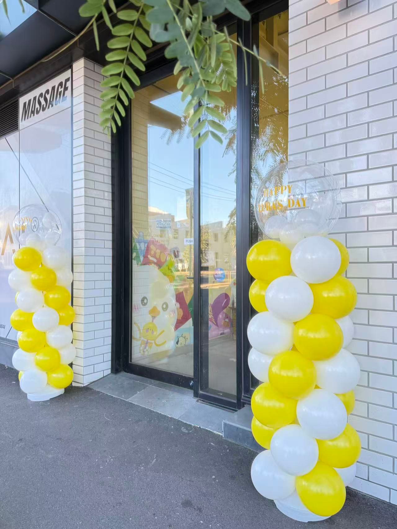 Storefront entrance with yellow and white spiral balloon columns