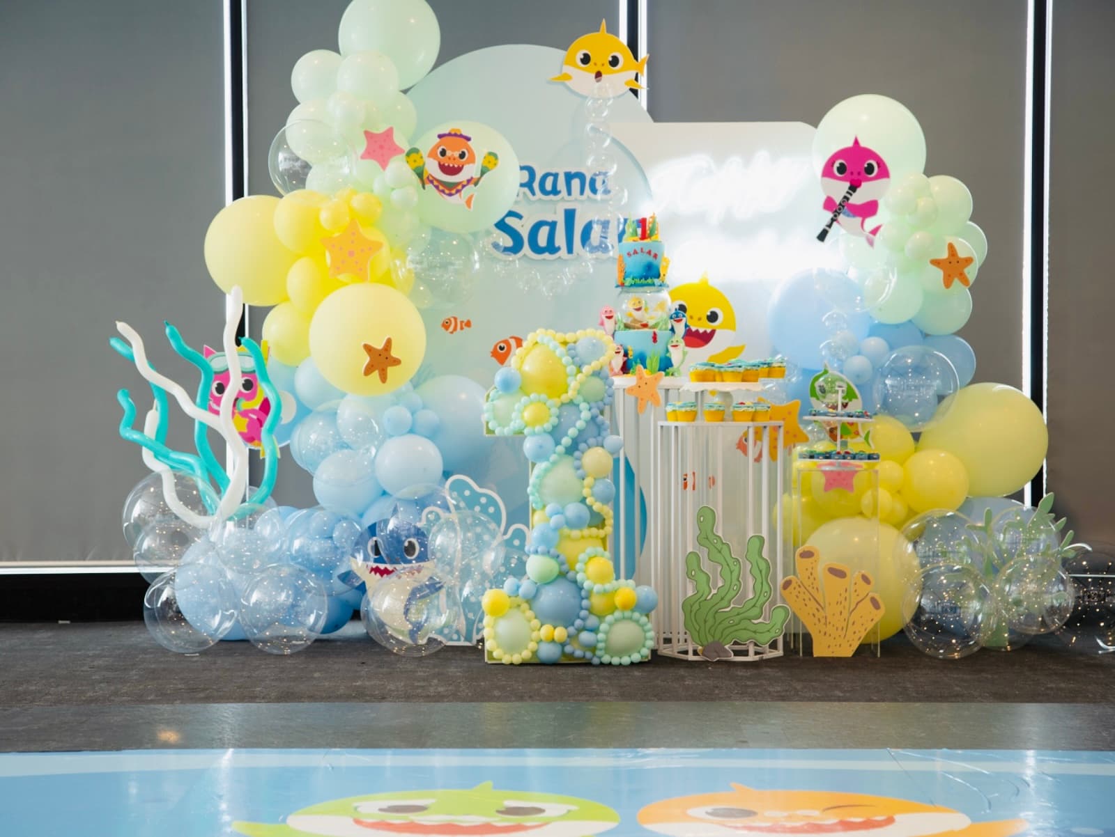 Baby Shark themed birthday with yellow, light blue, white and pink balloon arch and coral decorations