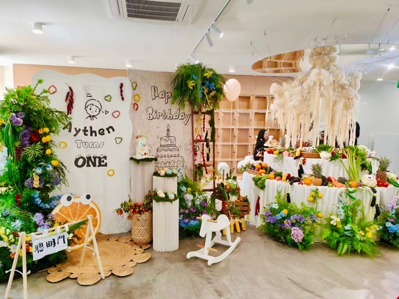 Garden themed 1st birthday for Aythen with lush greenery, white feathers and ONE sign