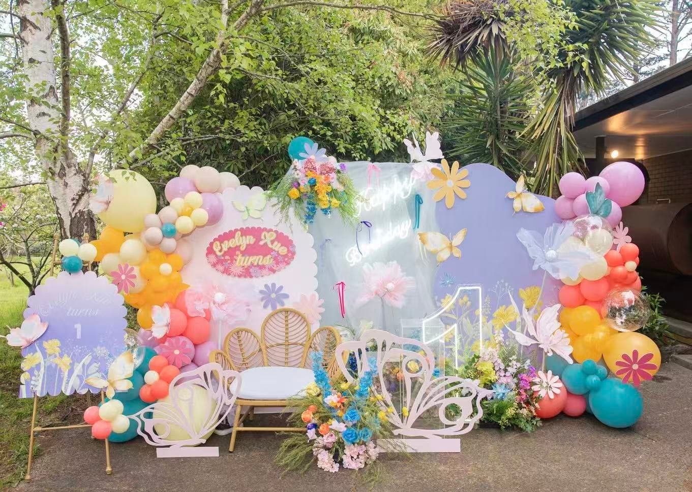 Pastel butterfly garden 1st birthday with outdoor backdrop and florals.