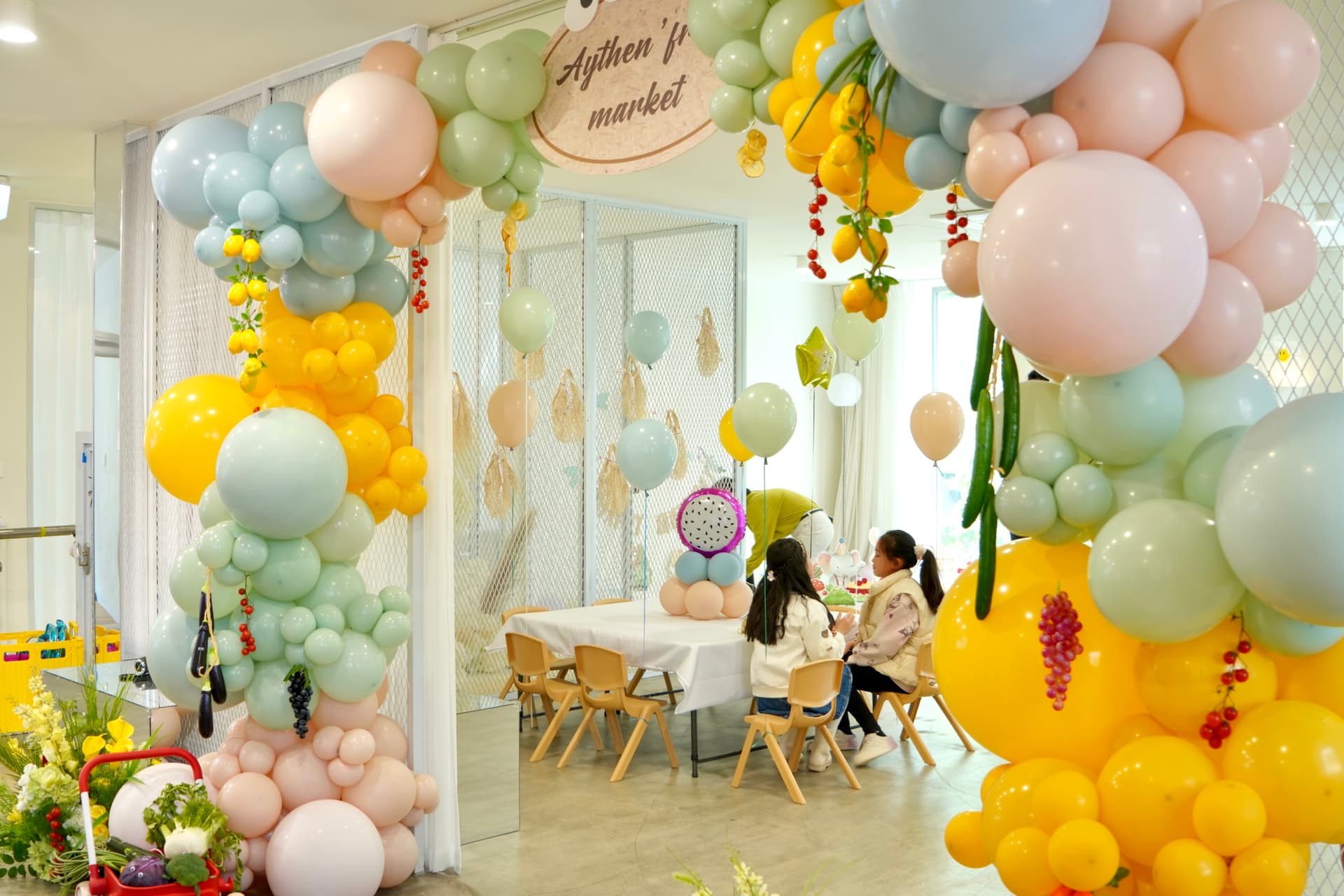 Pastel rainbow birthday with pink, orange, yellow, green and blue balloon arch and cake table