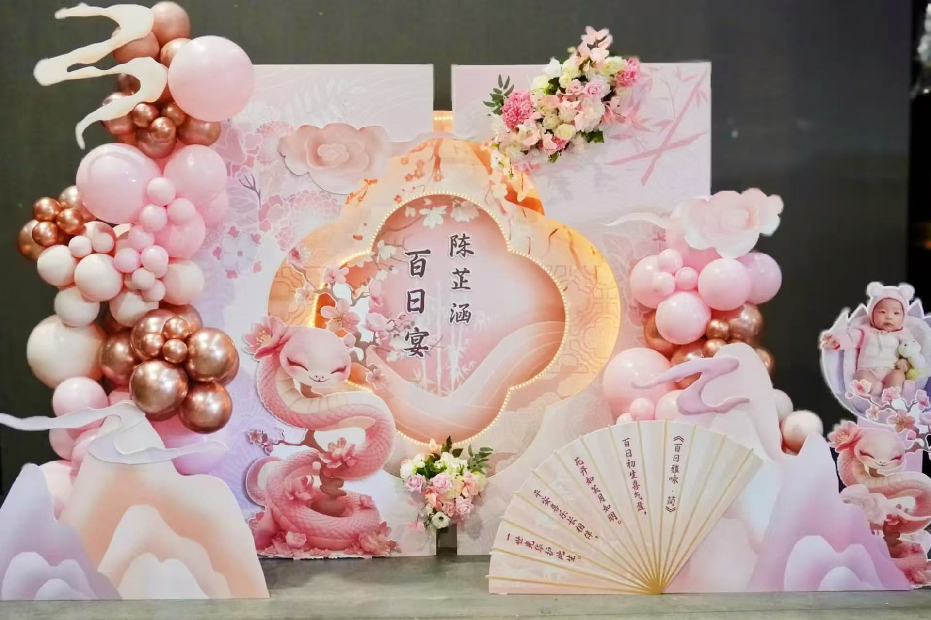 Elegant pink cherry blossom Chinese 100 days celebration with bespoke backdrop, fan prop and floral accents.