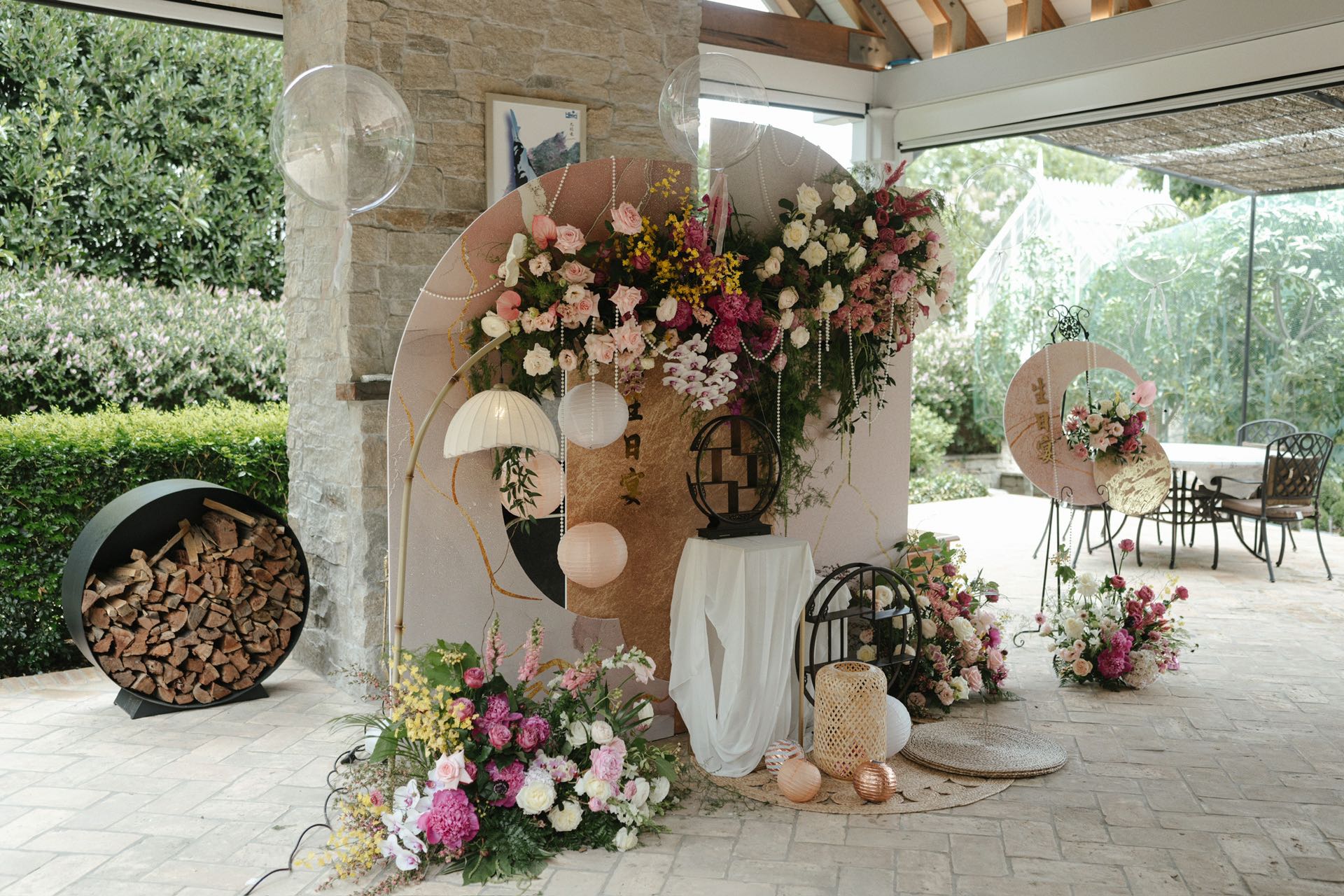 Rustic garden birthday setup with floral arrangements, transparent balloons and vintage lanterns