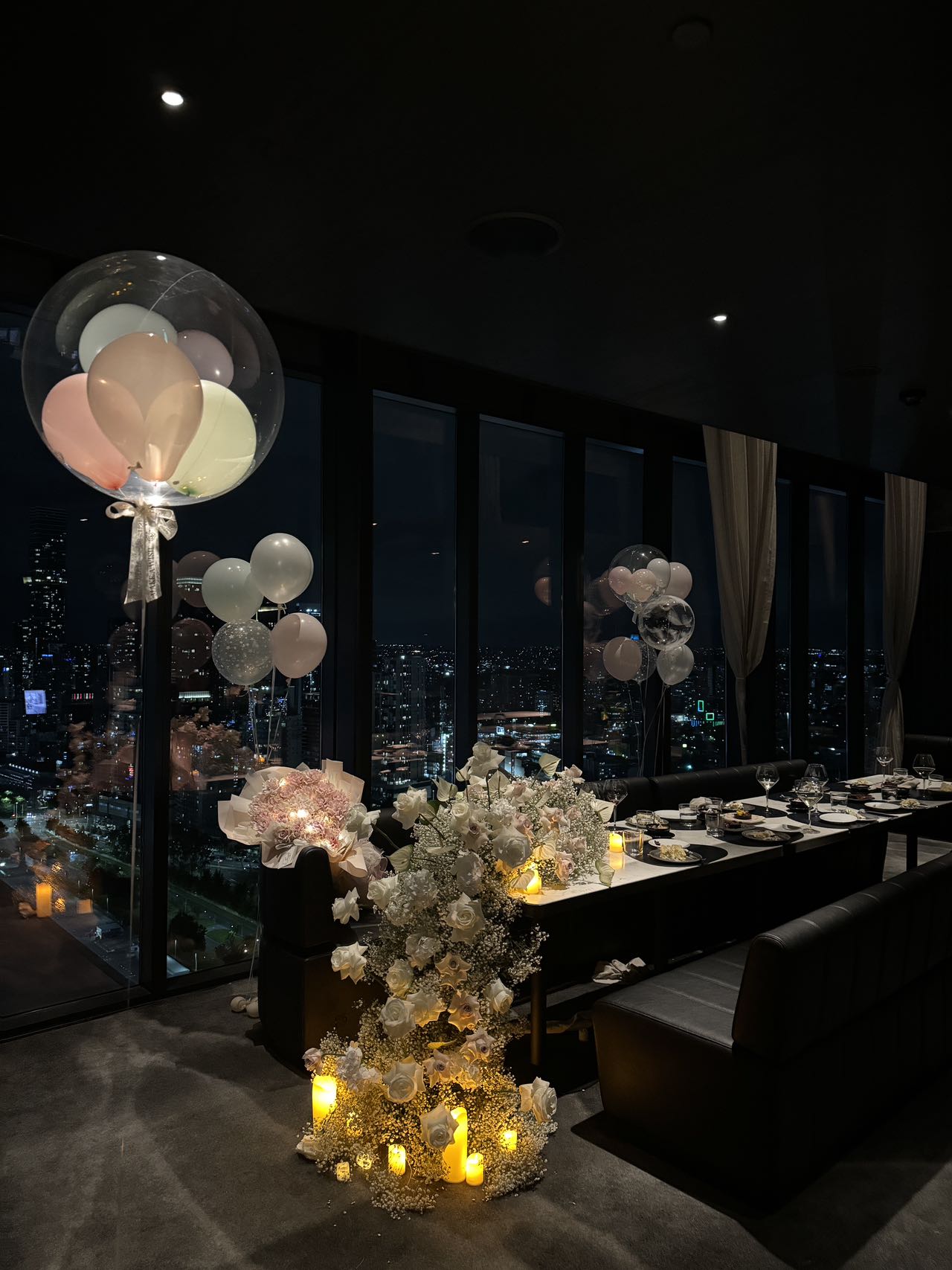 Luxurious high-rise restaurant birthday setup with transparent balloons and candles