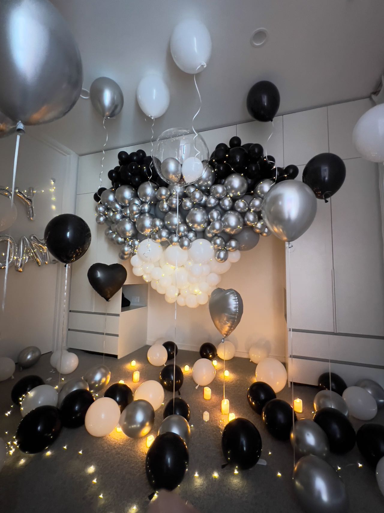 Elegant monochrome balloon decoration with LED string lights and candles