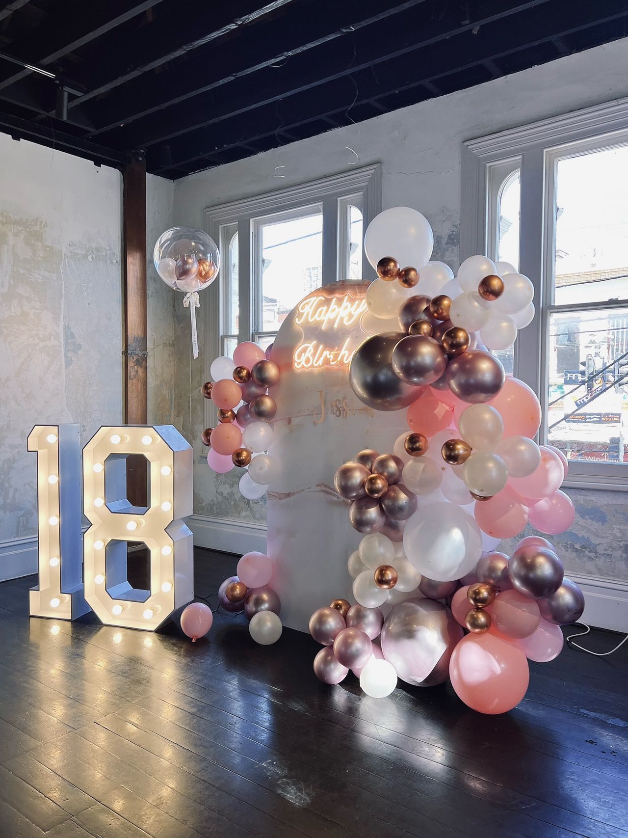 Modern 18th birthday setup with neon sign and rose gold balloons