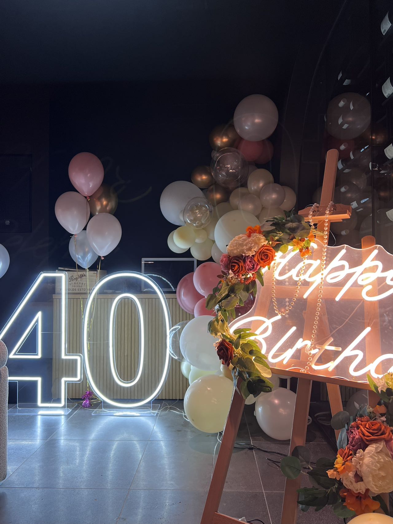 Glamorous 40th birthday setup with LED number lights, neon sign and pastel balloon garland