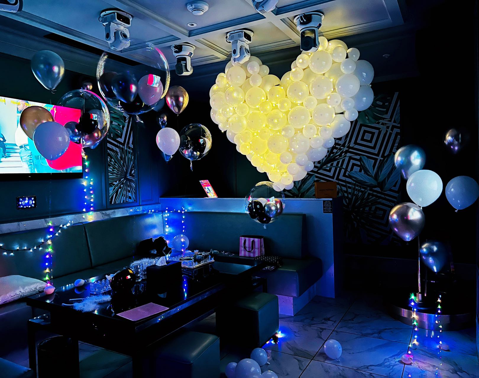 Nightclub style birthday setup with LED lights and heart-shaped balloon arrangement