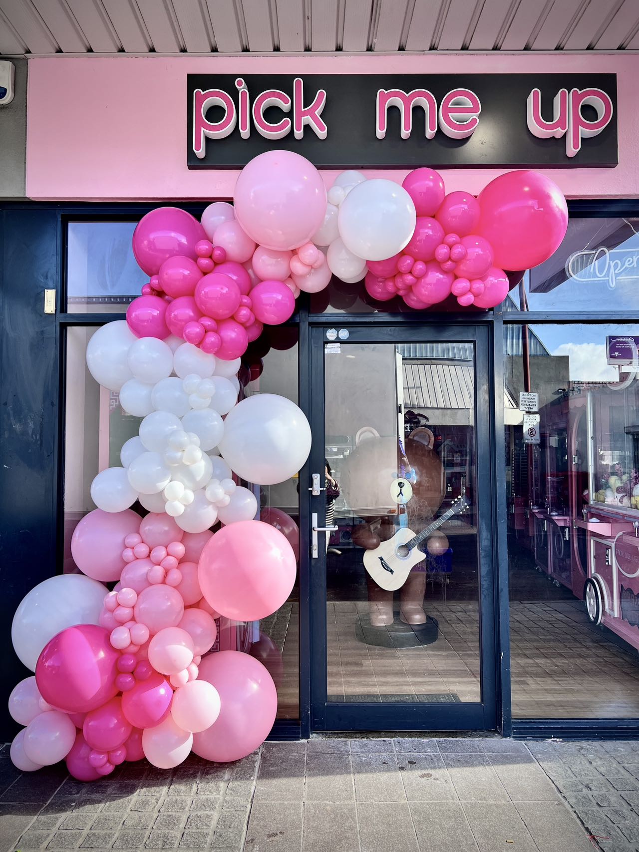 Pink and white balloon arch for store opening with neon signage