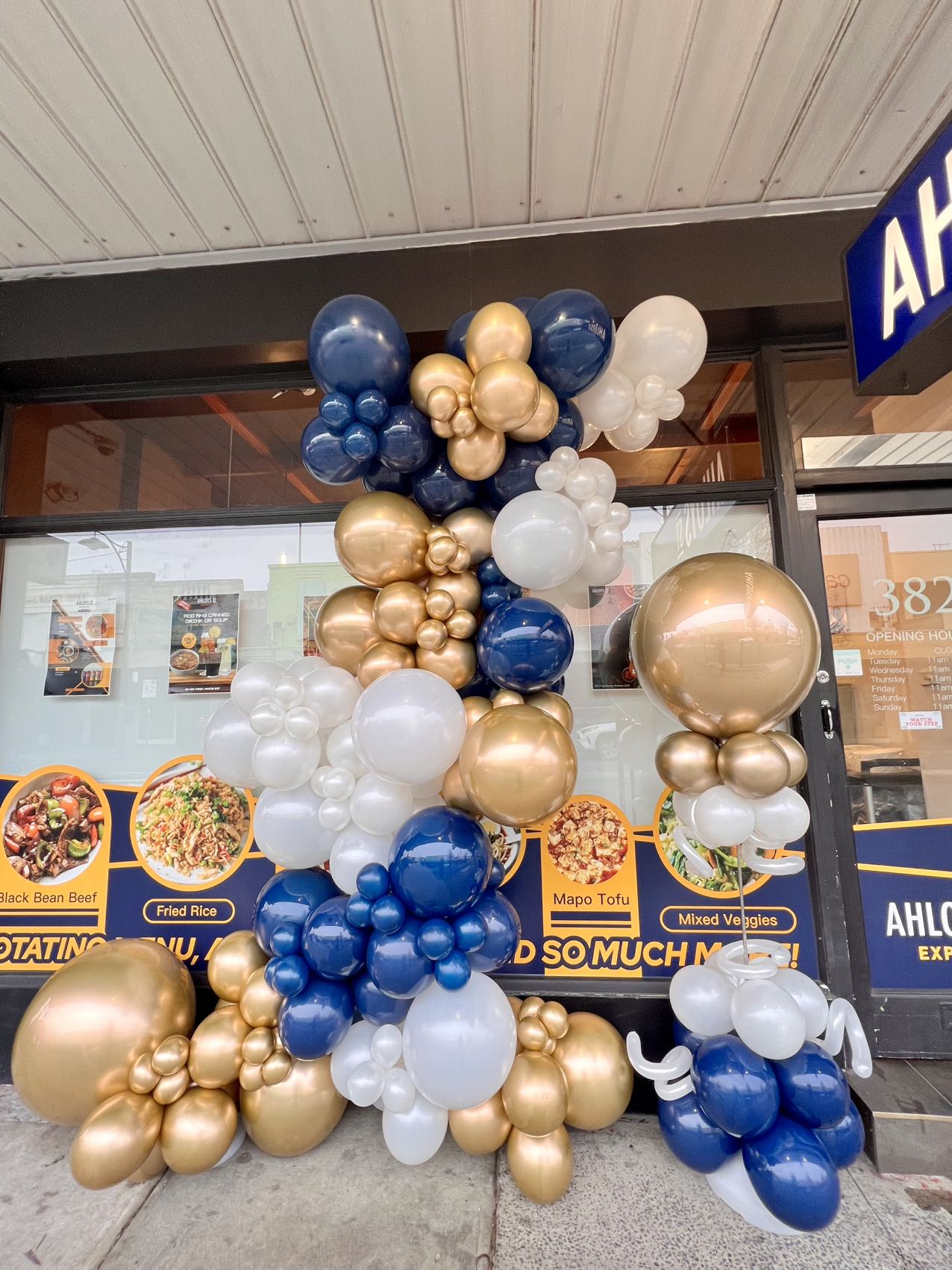 Restaurant entrance decorated with royal blue, gold, and white organic balloon arrangement