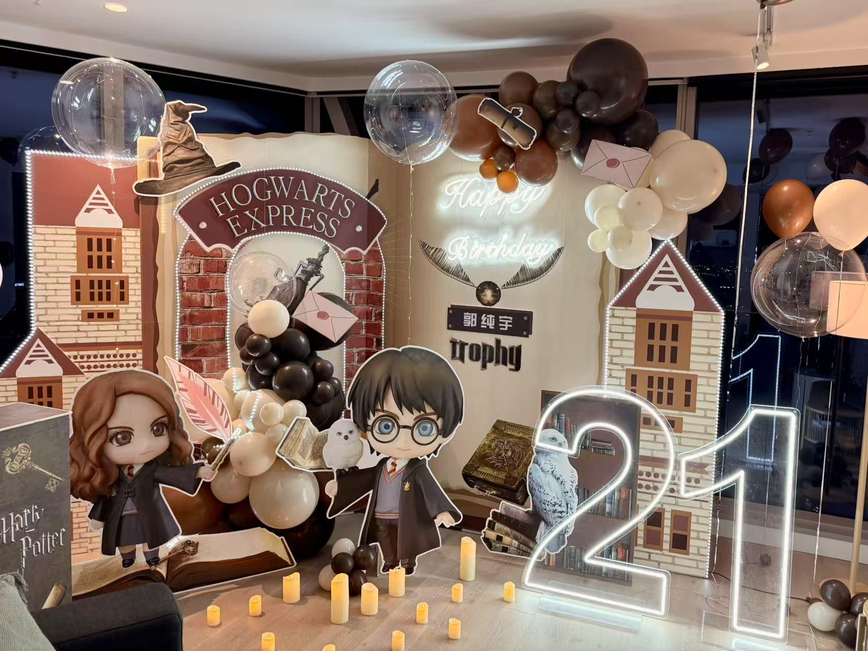 Magical Harry Potter themed 21st birthday featuring Hogwarts Express and Castle backdrop elements. Includes Harry and Hermione character cutouts, elegant brown and cream balloon arrangements, flying letters, and a neon number "21" light. Decorated with magical elements like owls, spellbooks, and floating candles for an enchanting wizarding world experience.