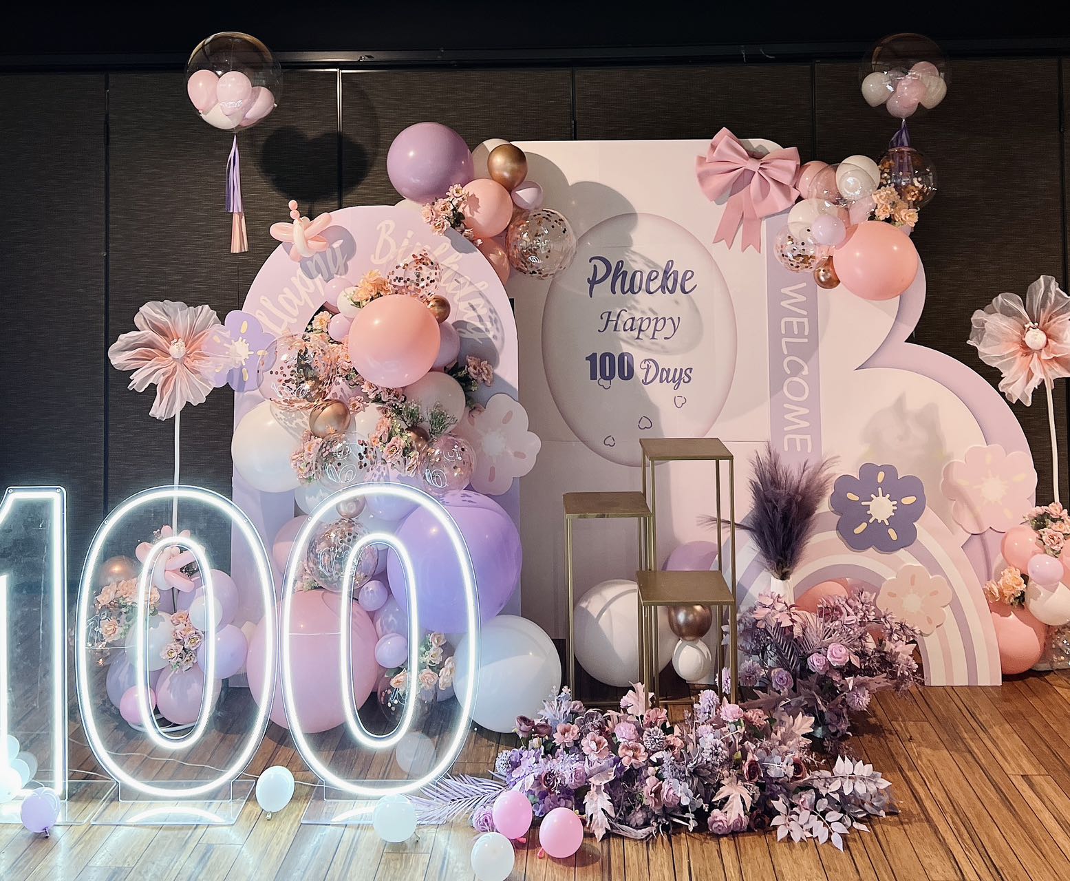 Dreamy 100 days celebration for Phoebe with LED number lights, pink and purple balloon garland, and floral decorations