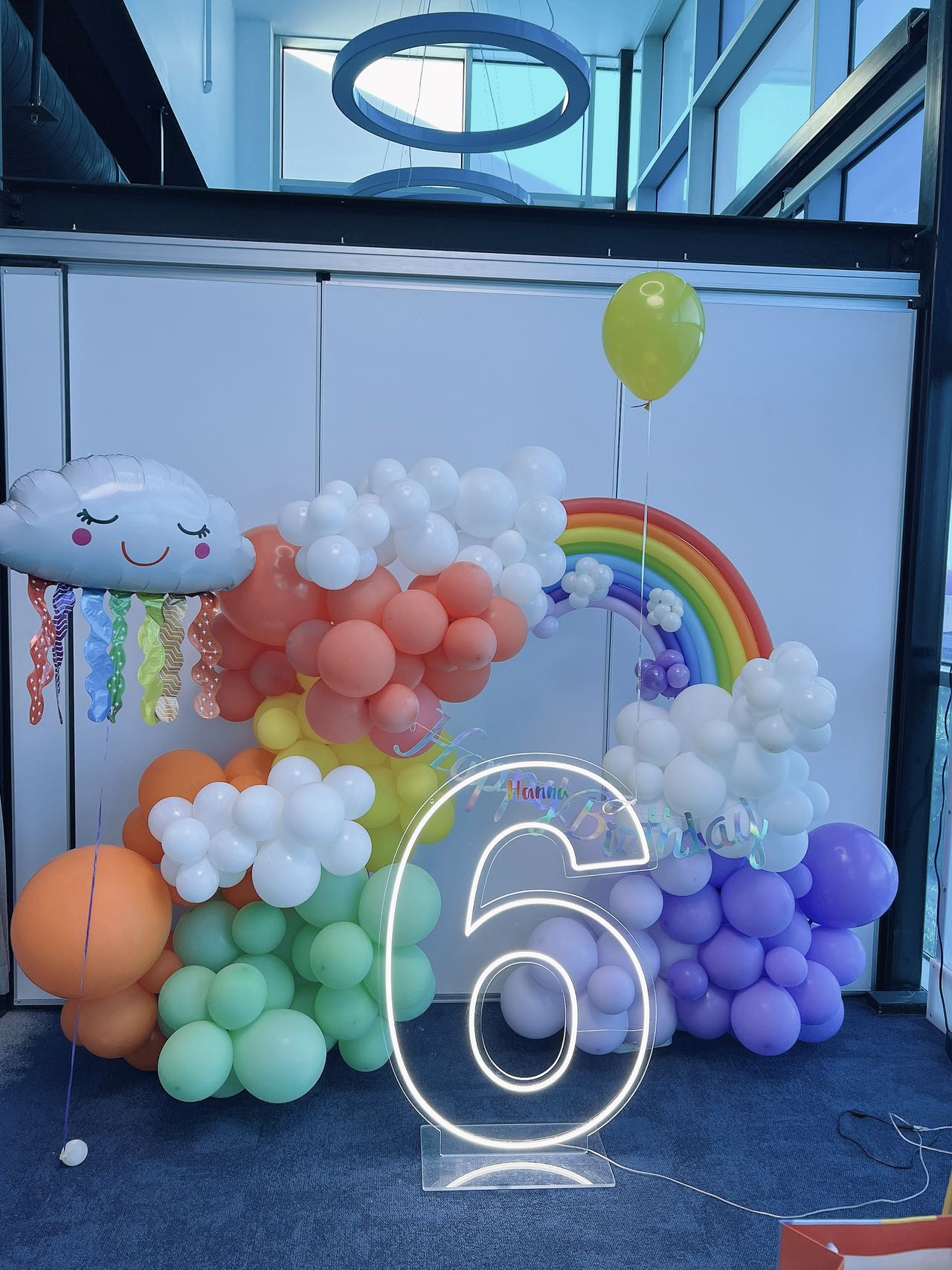 Colorful rainbow themed 6th birthday with cloud decorations and neon number light